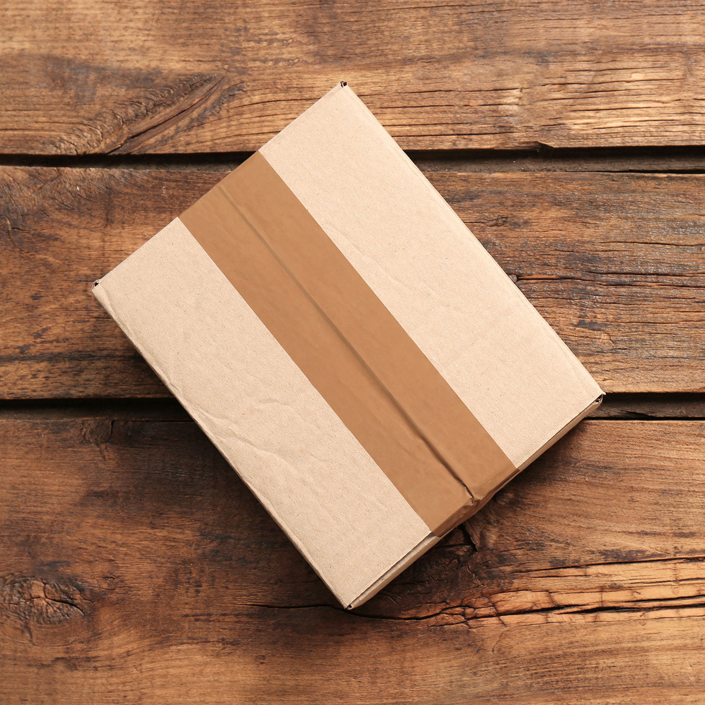 Photo of a taped cardboard box on a wooden floor.