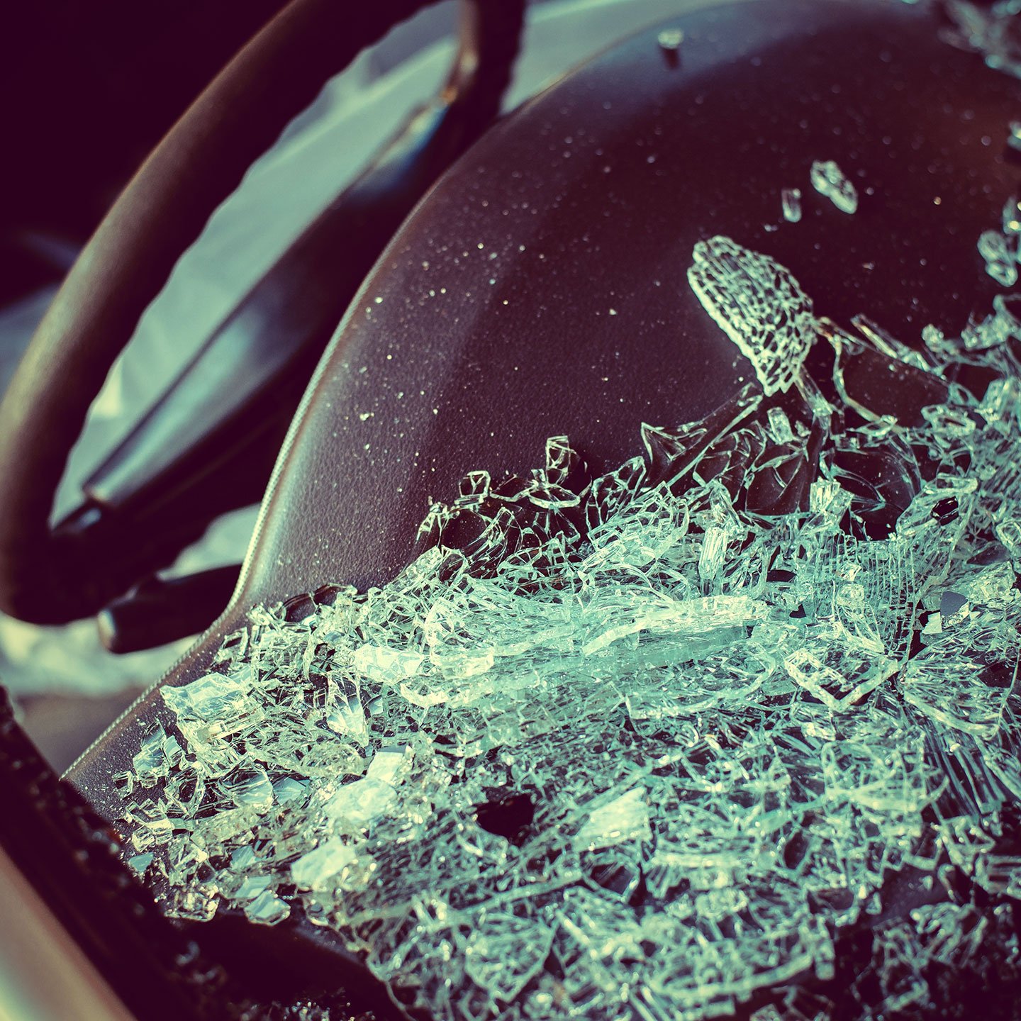 Close-up photo of a broken windshield laying on a dashboard