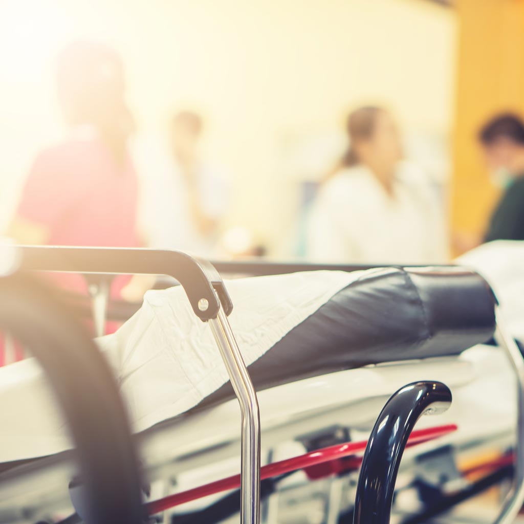 An empty hospital bed in a busy hallway